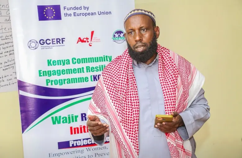 Programme participant in front of the Kenya Community Engagement and Resilience Programme banner